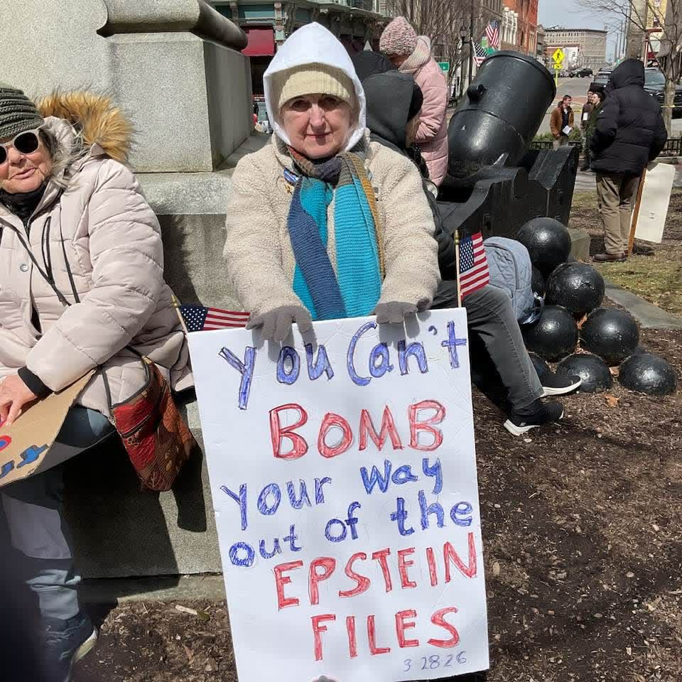 A protester holds a handmade 'You can't bomb your way out of the Epstein files' sign at the Broome County Courthouse